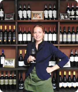 A woman smiling while enjoying a glass of wine